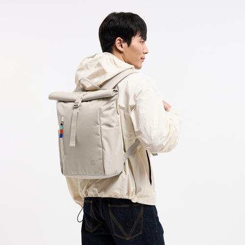 ROLLTOP EASY SMALL Rucksack in soft shell (warmes Cremeweiß) von einem Mann auf dem Rücken getragen.