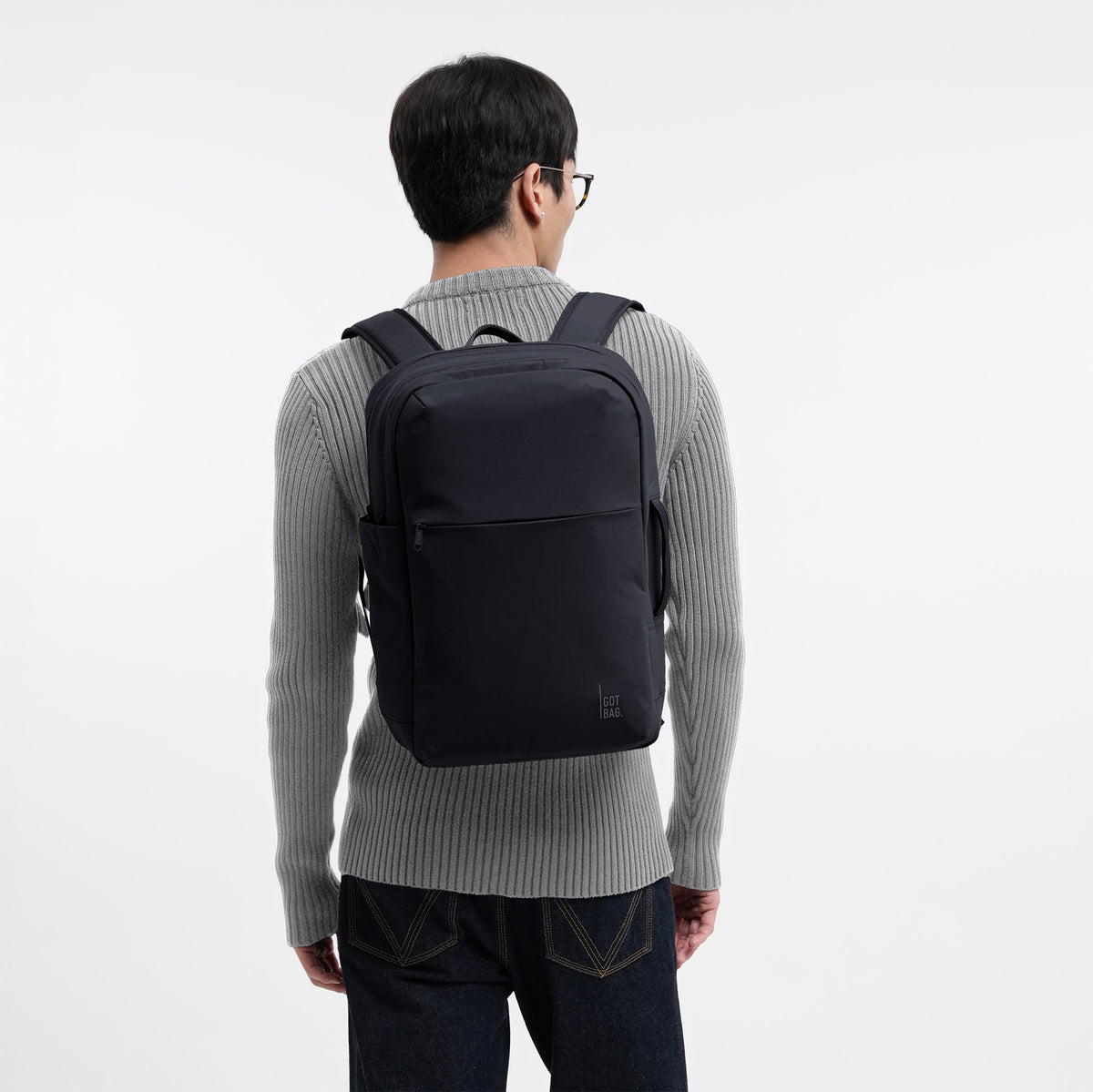 COMMUTER PACK Rucksack in black (Schwarz) von einem Mann auf dem Rücken getragen.
