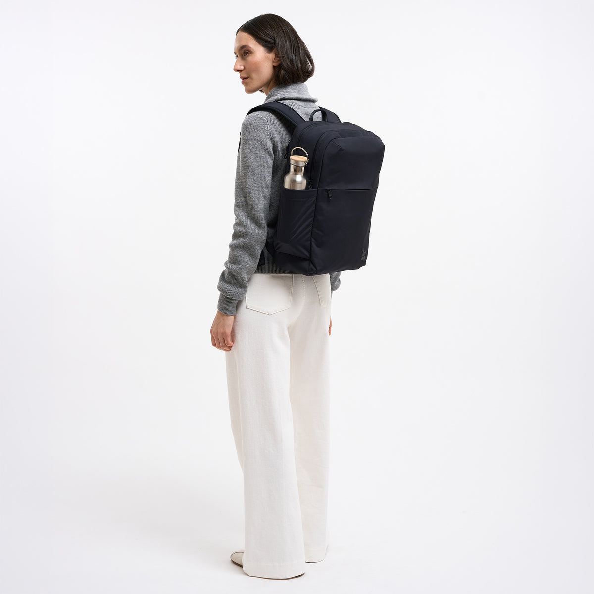 COMMUTER PACK Rucksack in black (Schwarz) von einer Frau auf dem Rücken getragen.