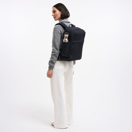 COMMUTER PACK Rucksack in black (Schwarz) von einer Frau auf dem Rücken getragen.