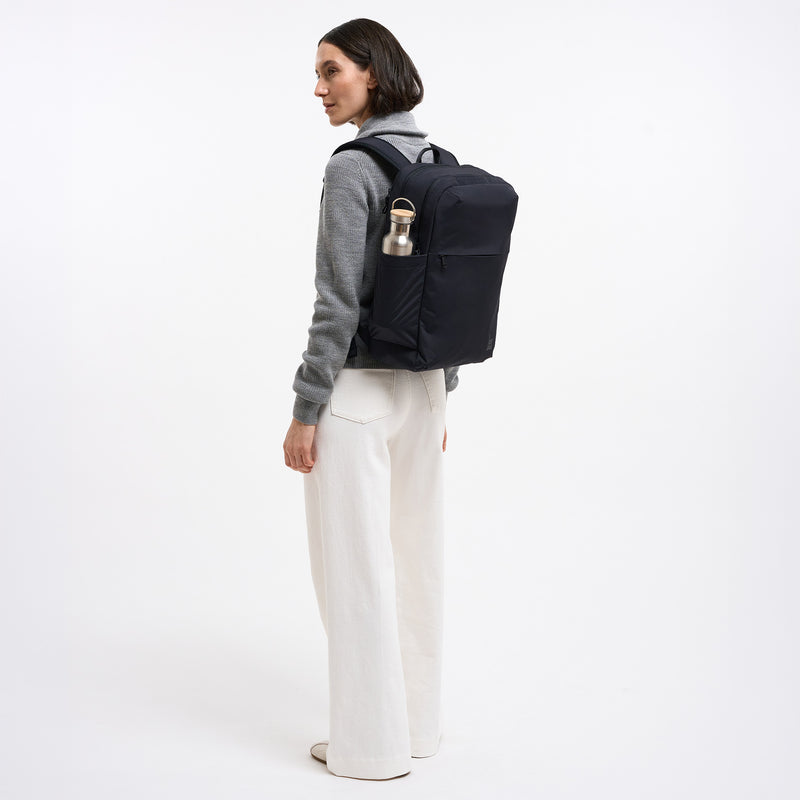 COMMUTER PACK Rucksack in black (Schwarz) von einer Frau auf dem Rücken getragen.