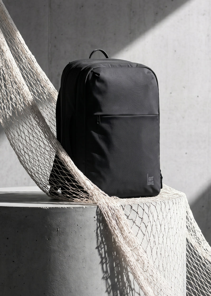 COMMUTER PACK zaino in nero (nero) appoggiato su un cilindro di cemento con rete.