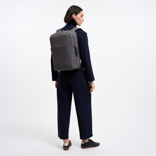 COMMUTER PACK Rucksack in shark (Dunkelgrau) von einer Frau als Rucksack auf dem Rücken getragen.