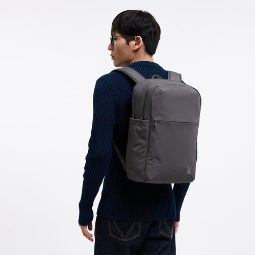 COMMUTER PACK Rucksack in shark (Dunkelgrau) von einem Mann auf dem Rücken getragen.