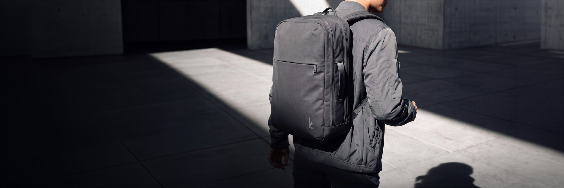 COMMUTER PACK Rucksack in shark (Dunkelgrau) von einem Mann als Rucksack auf dem Rücken getragen.