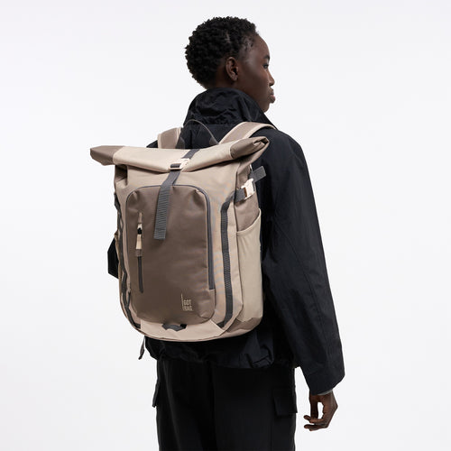 ROLLTOP ADVENTURE MONOCHROME Rucksack in oyster (klassisches Taupe-Braun) von einer Frau als Rucksack auf dem Rücken getragen.
