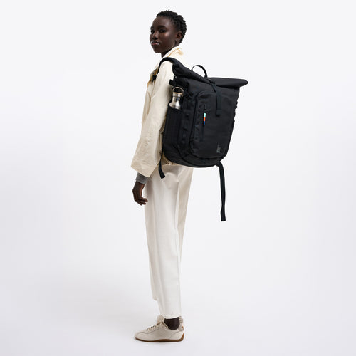 BP0201XX ROLLTOP ADVENTURE Rucksack in black (Schwarz) von einer Frau mit Flasche getragen.