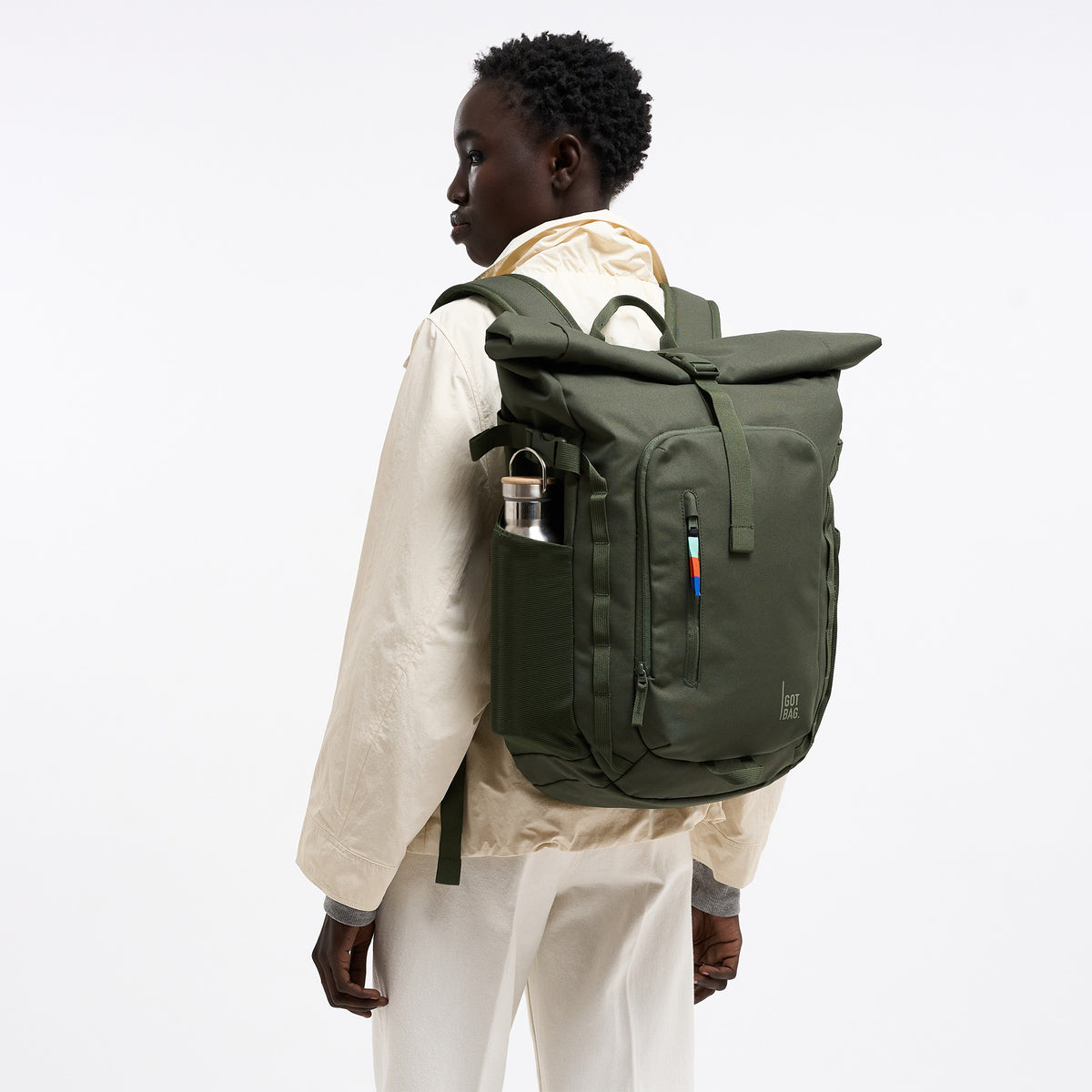 ROLLTOP ADVENTURE Rucksack in algae (Dunkelgrün mit Graustich) von einer Frau auf dem Rücken getragen, mit Trinkflasche.