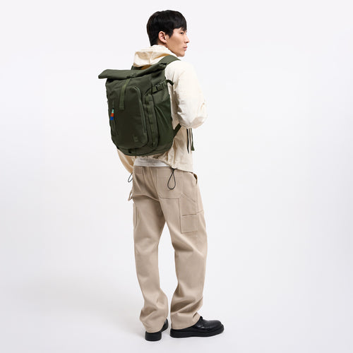 ROLLTOP ADVENTURE Rucksack in algae (Dunkelgrün mit Graustich) von einem Mann auf dem Rücken getragen.