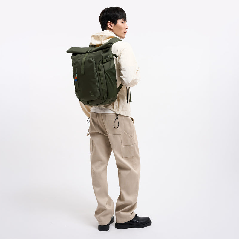 ROLLTOP ADVENTURE Rucksack in algae (Dunkelgrün mit Graustich) von einem Mann auf dem Rücken getragen.