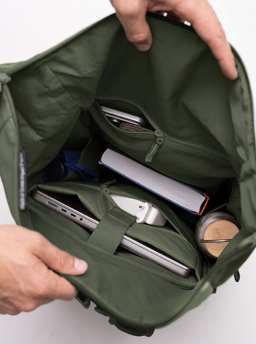 ROLLTOP ADVENTURE Rucksack in algae (Dunkelgrün mit Graustich) von Händen geöffnet, mit Inhalt.