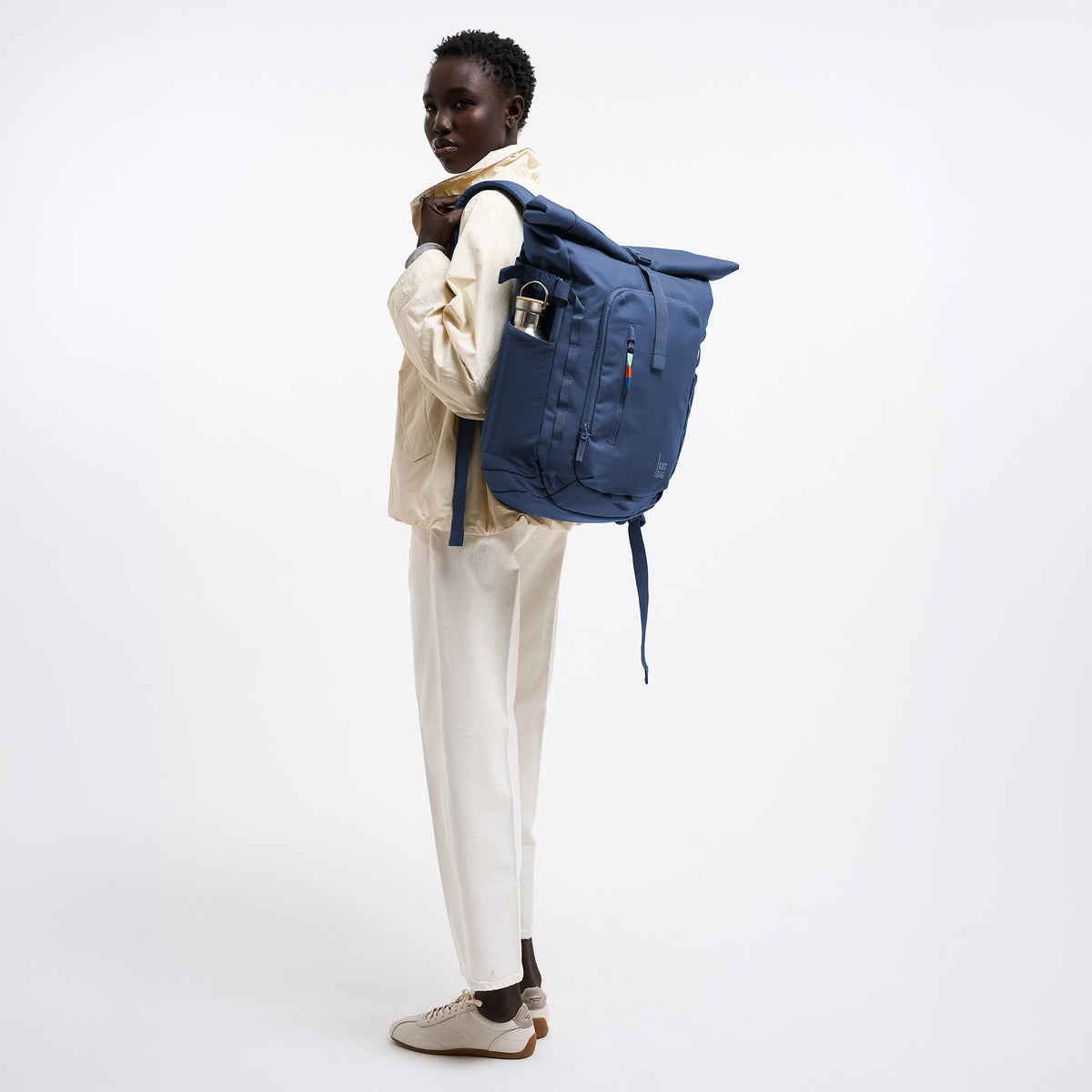 ROLLTOP ADVENTURE Rucksack in ocean blue (Marineblau) von einer Frau als Rucksack auf dem Rücken getragen.