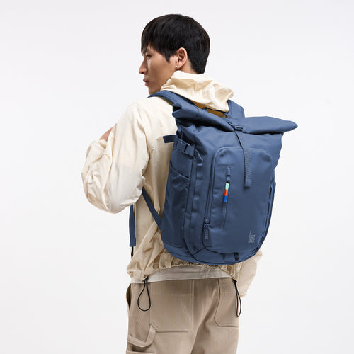 ROLLTOP ADVENTURE Rucksack in ocean blue (Marineblau) von einem Mann auf dem Rücken getragen.