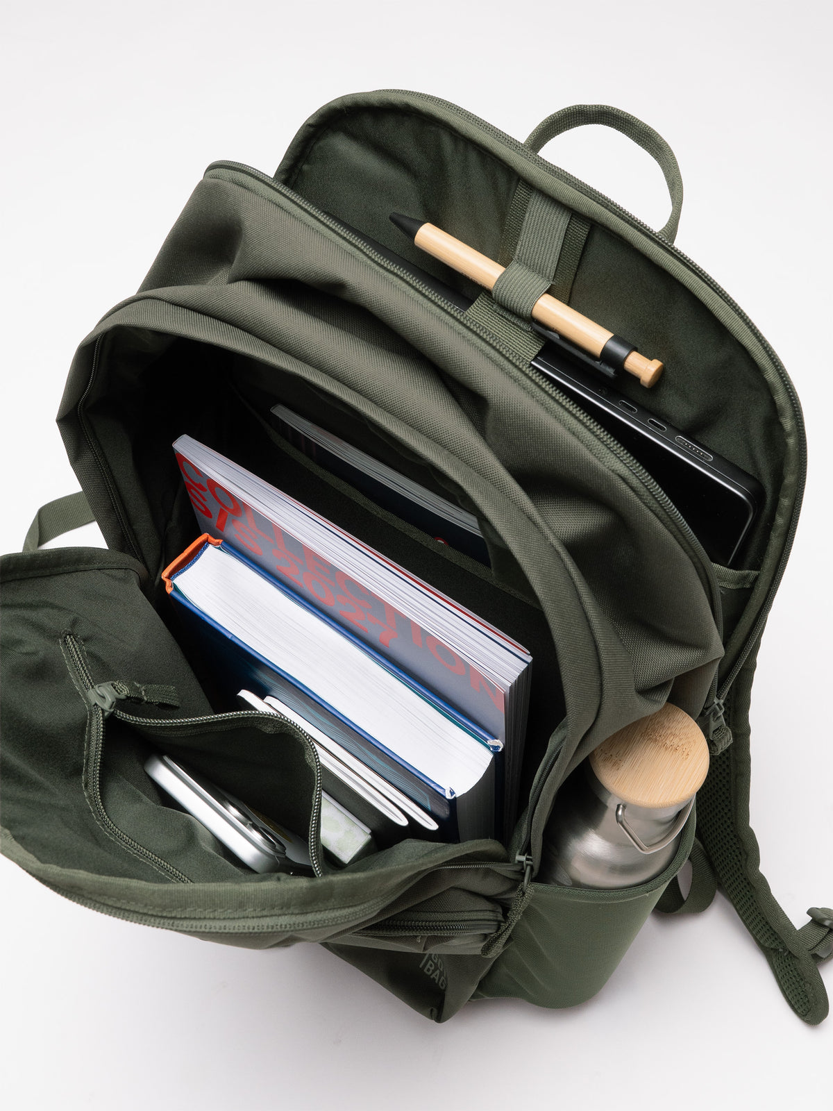 BASE PACK Rucksack in algae (Dunkelgrün mit Graustich) von oben, gefüllt mit Büchern, Handy und Flasche.