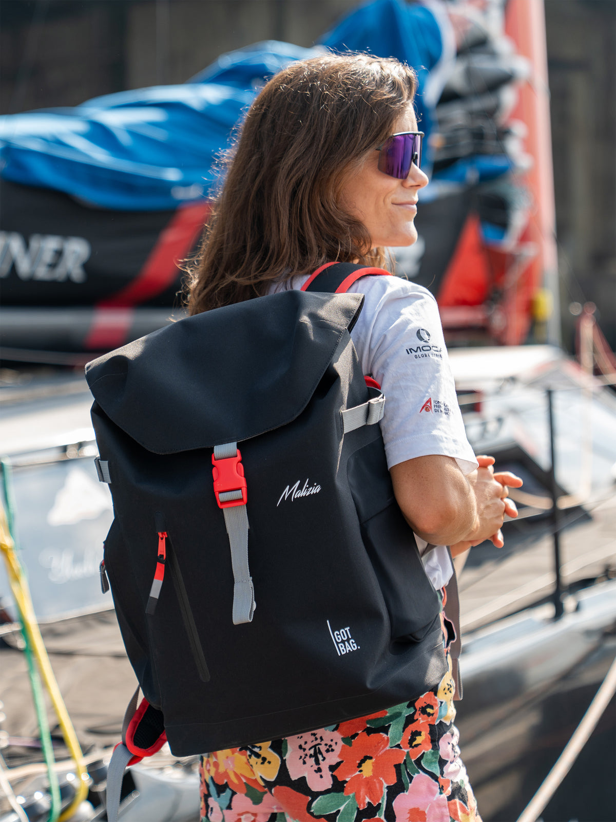 MALIZIA PACK Rucksack in black (Schwarz) von einer Frau im Freien als Rucksack auf dem Rücken getragen.