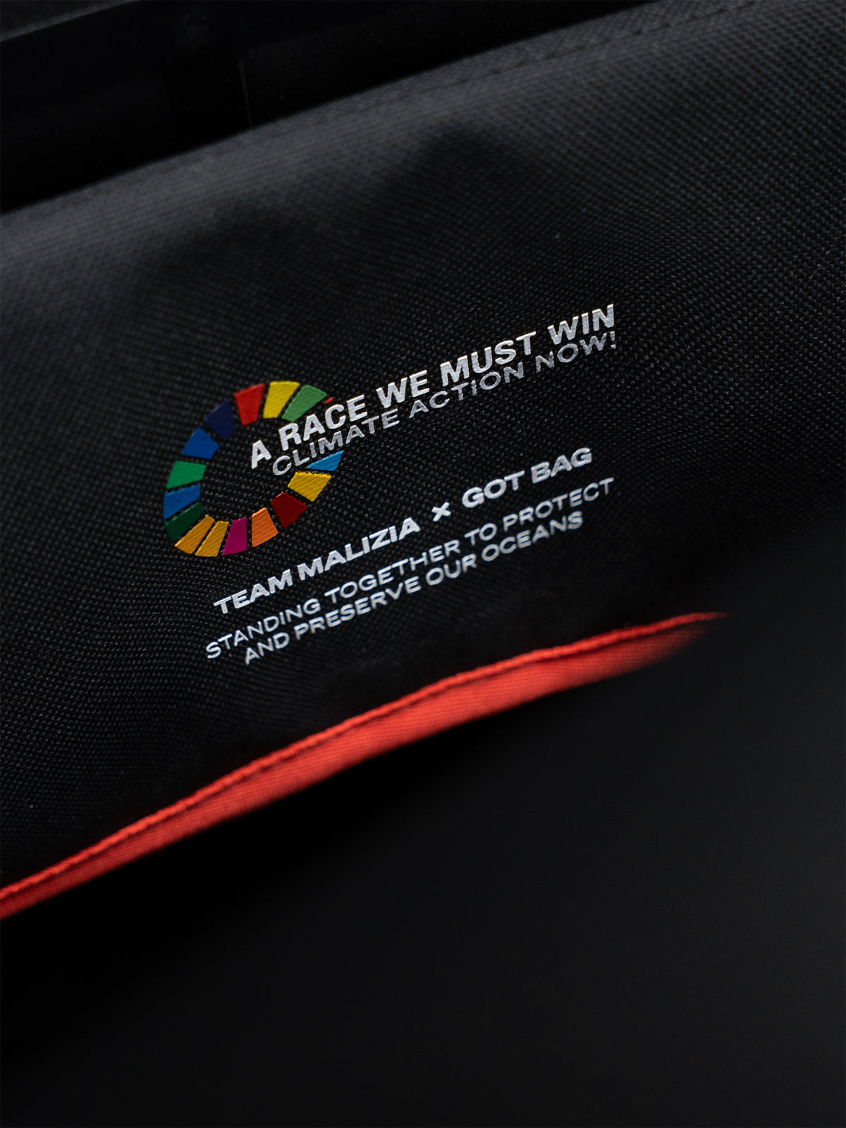 MALIZIA PACK Tasche in black (Schwarz), Detailaufnahme des Innenbereichs mit rotem Saum, Logo und Schriftzug.