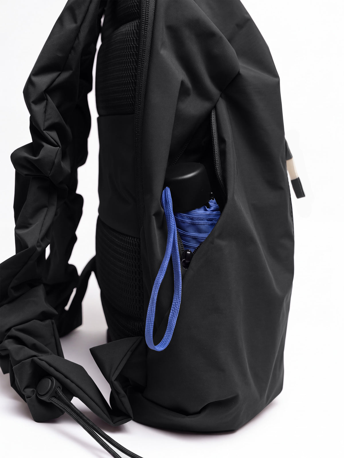 RUFFLE PACK Rucksack in black (Schwarz), Seitenansicht mit offener Tasche und blauem Regenschirm.