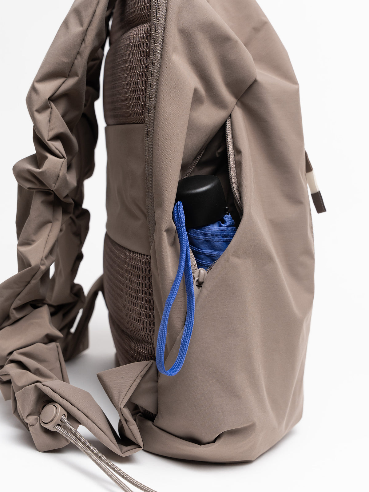 RUFFLE PACK Rucksack in oyster (klassisches Taupe-Braun), Detailaufnahme einer Seitentasche mit blauem Schirm.
