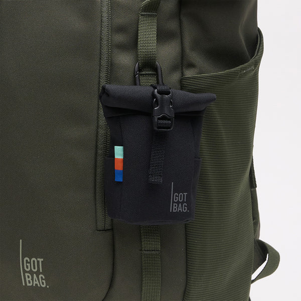 ROLLTOP CHARM Accessoire in black (Schwarz) als Detailaufnahme befestigt an einem Rucksack in algae (Dunkelgrün mit Graustich).