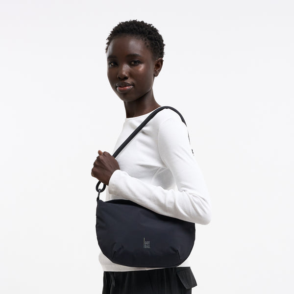 CLAM BAG Tasche in black (Schwarz) von einer Frau über der Schulter getragen.