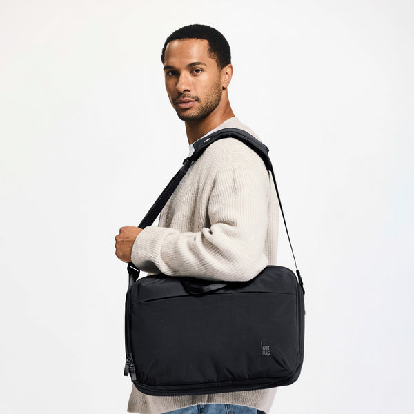 COMMUTER BAG Tasche in black (Schwarz) von einem Mann über der Schulter getragen.