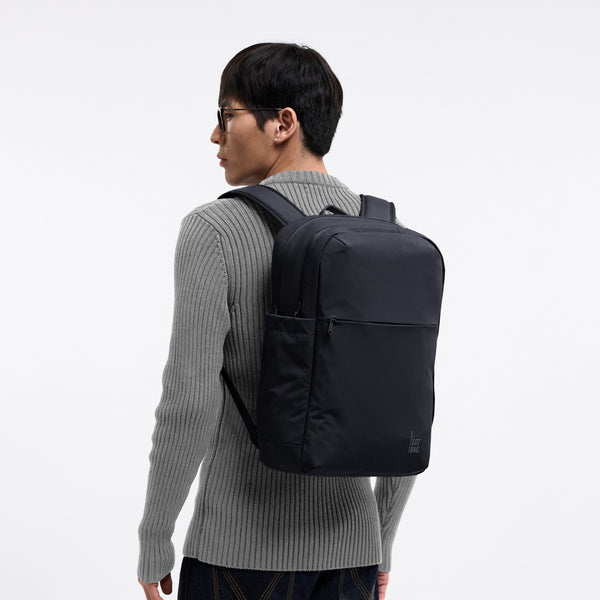 COMMUTER PACK Rucksack in black (Schwarz) von einem Mann als Rucksack auf dem Rücken getragen.