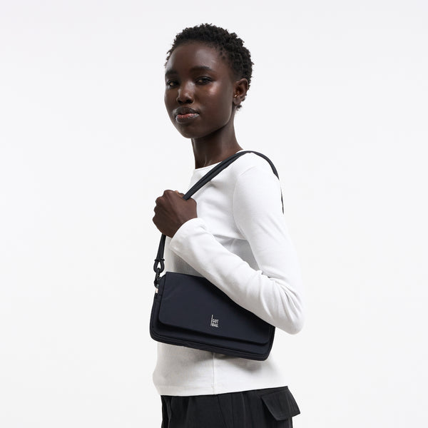 FACET BAG Tasche in black (Schwarz) von einer Frau crossbody getragen.