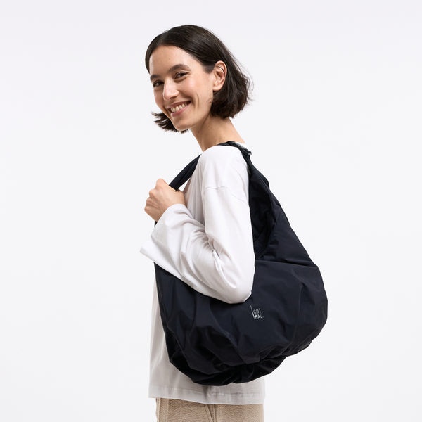 FULL MOON BAG Tasche in black (Schwarz) von einer Frau über der Schulter getragen.