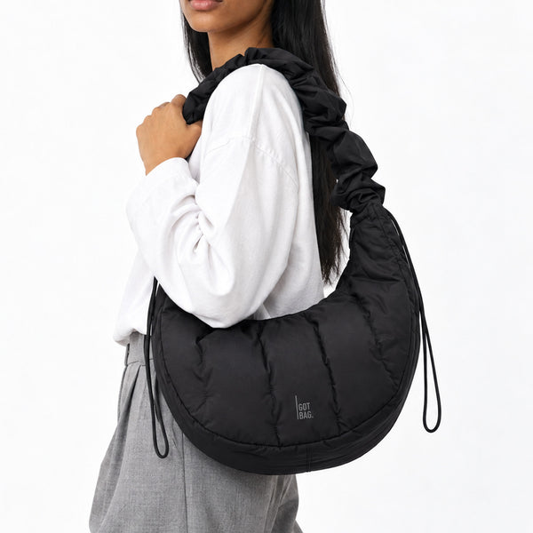 LOOMI RUFFLE BAG Tasche in black (Schwarz) von einer Frau über der Schulter getragen.