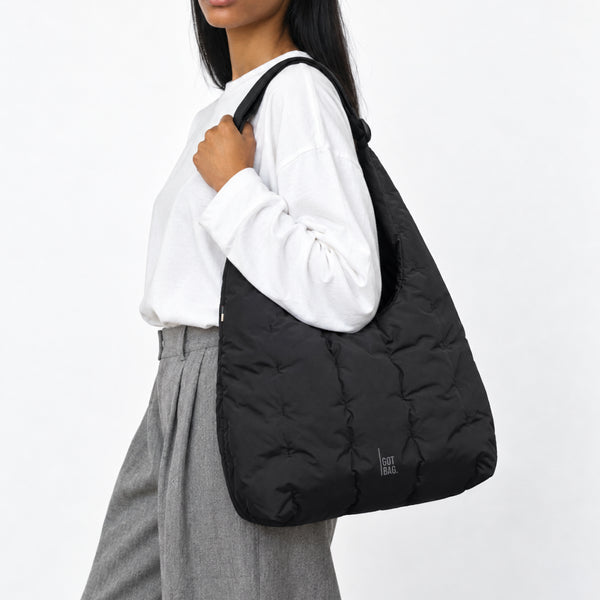 LOOMI SHOULDER BAG Tasche in black (Schwarz) von einer Frau über der Schulter getragen.