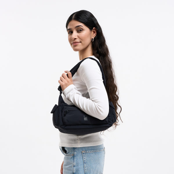 POCKET BAG SMALL Tasche in black (Schwarz) von einer Frau über der Schulter getragen.