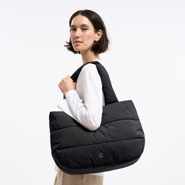 BUBBLE PUFFER HORIZON TOTE Tasche in black (Schwarz) von einer Frau über der Schulter getragen.