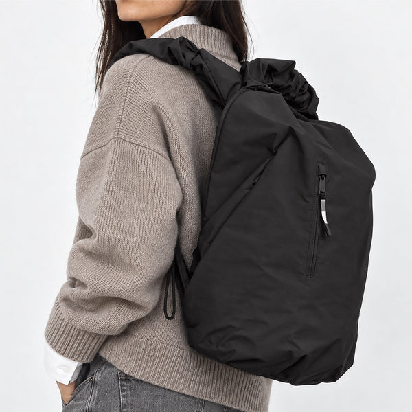 RUFFLE PACK Rucksack in black (Schwarz) von einer Frau als Rucksack auf dem Rücken getragen.