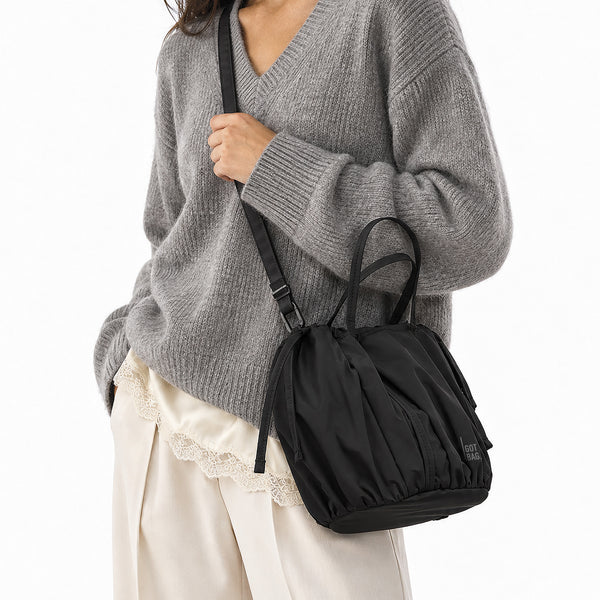 SHELLY BUCKET BAG Tasche in black (Schwarz) von einer Frau crossbody getragen.