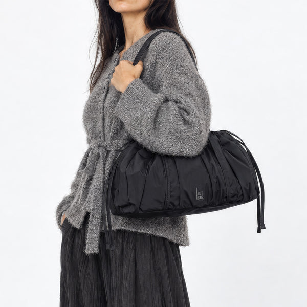 SHELLY SHOULDER BAG Tasche in black (Schwarz) von einer Frau über der Schulter getragen.