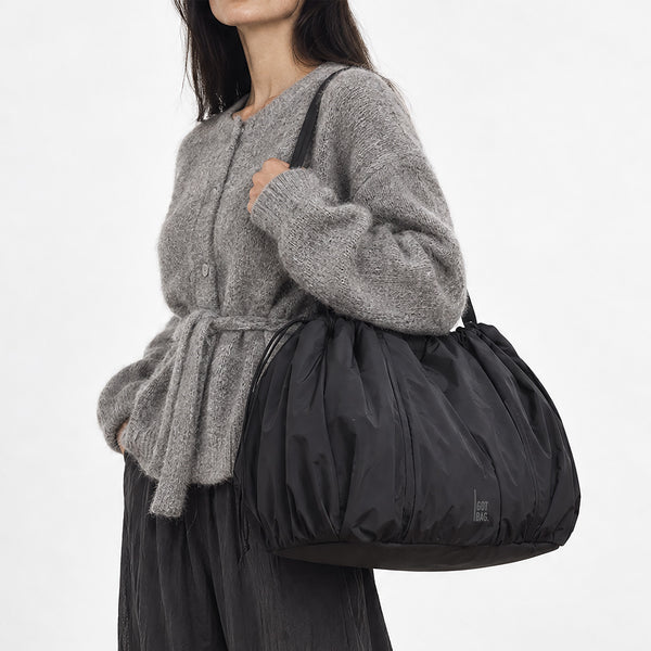 SHELLY TOTE BAG Tasche in black (Schwarz) von einer Frau über der Schulter getragen.