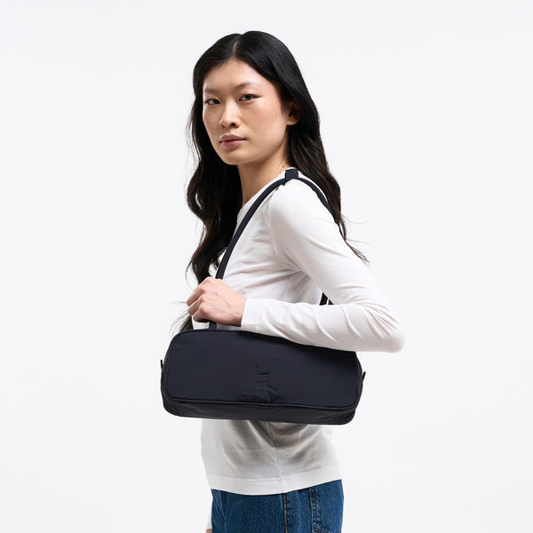 STRIKE BAG SMALL Tasche in black (Schwarz) von einer Frau über der Schulter getragen.