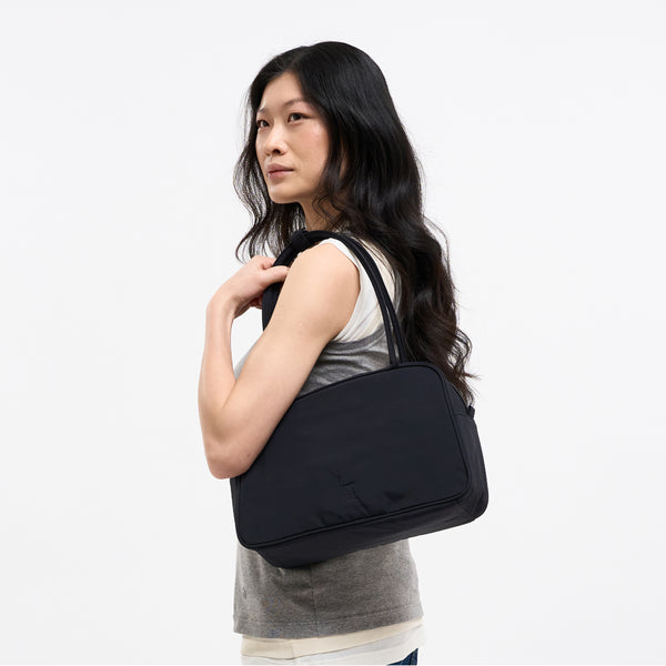 STRIKE BAG Tasche in black (Schwarz) von einer Frau über der Schulter getragen.