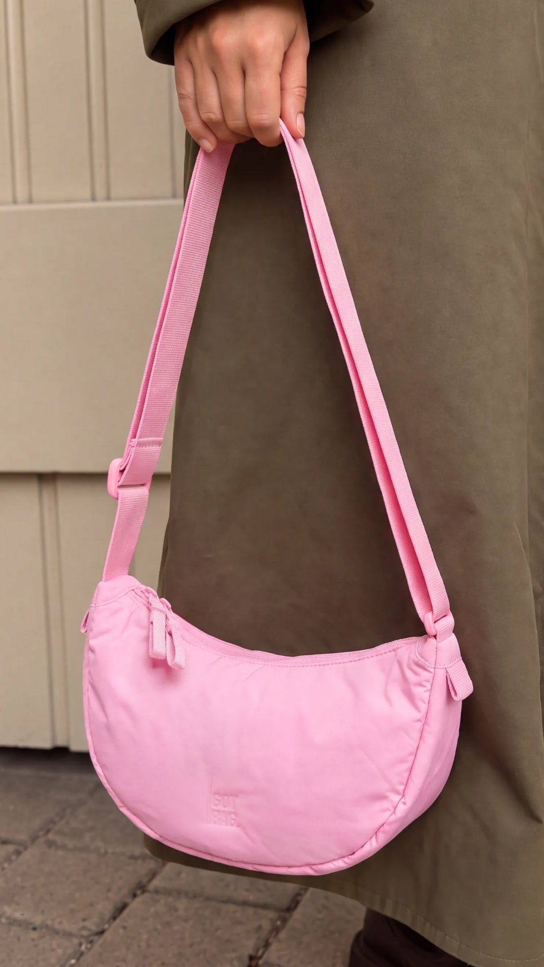 CLOUD MOON BAG SMALL sac en sea rose (rose pastel intense) tenu par une femme dans sa main.