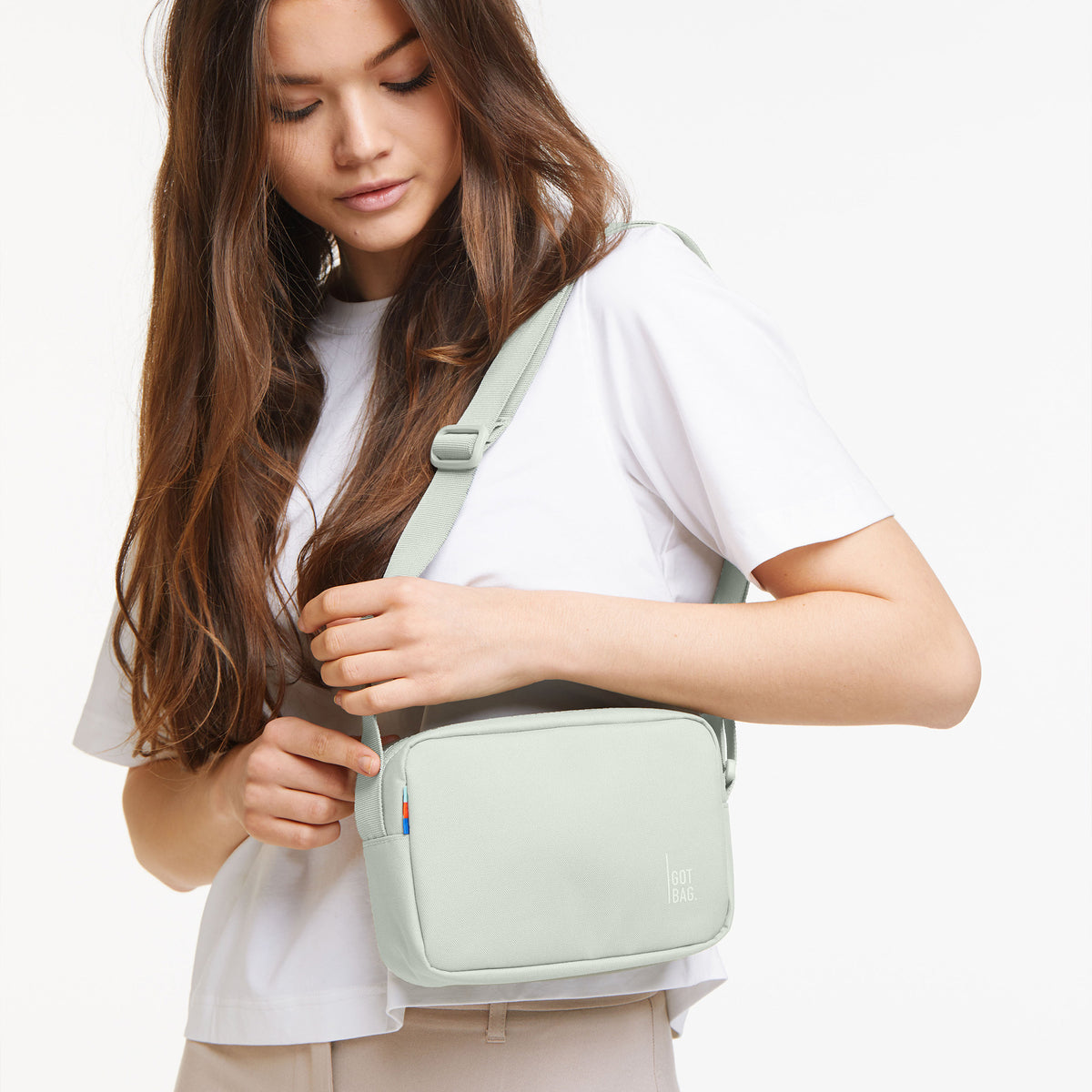 CROSSBODY BAG Tasche in eel (sehr helles Grün/Mint) von einer Frau crossbody getragen.