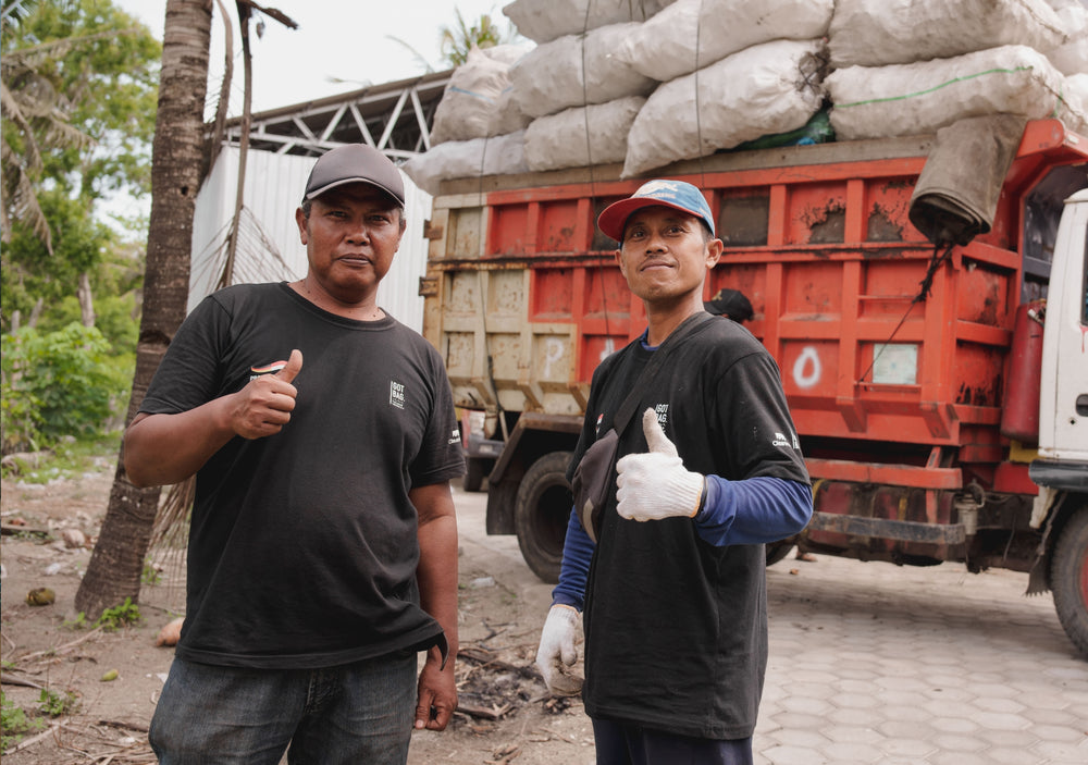 Zwei Männer geben Daumen hoch vor einem roten LKW, der mit weißen Säcken beladen ist.