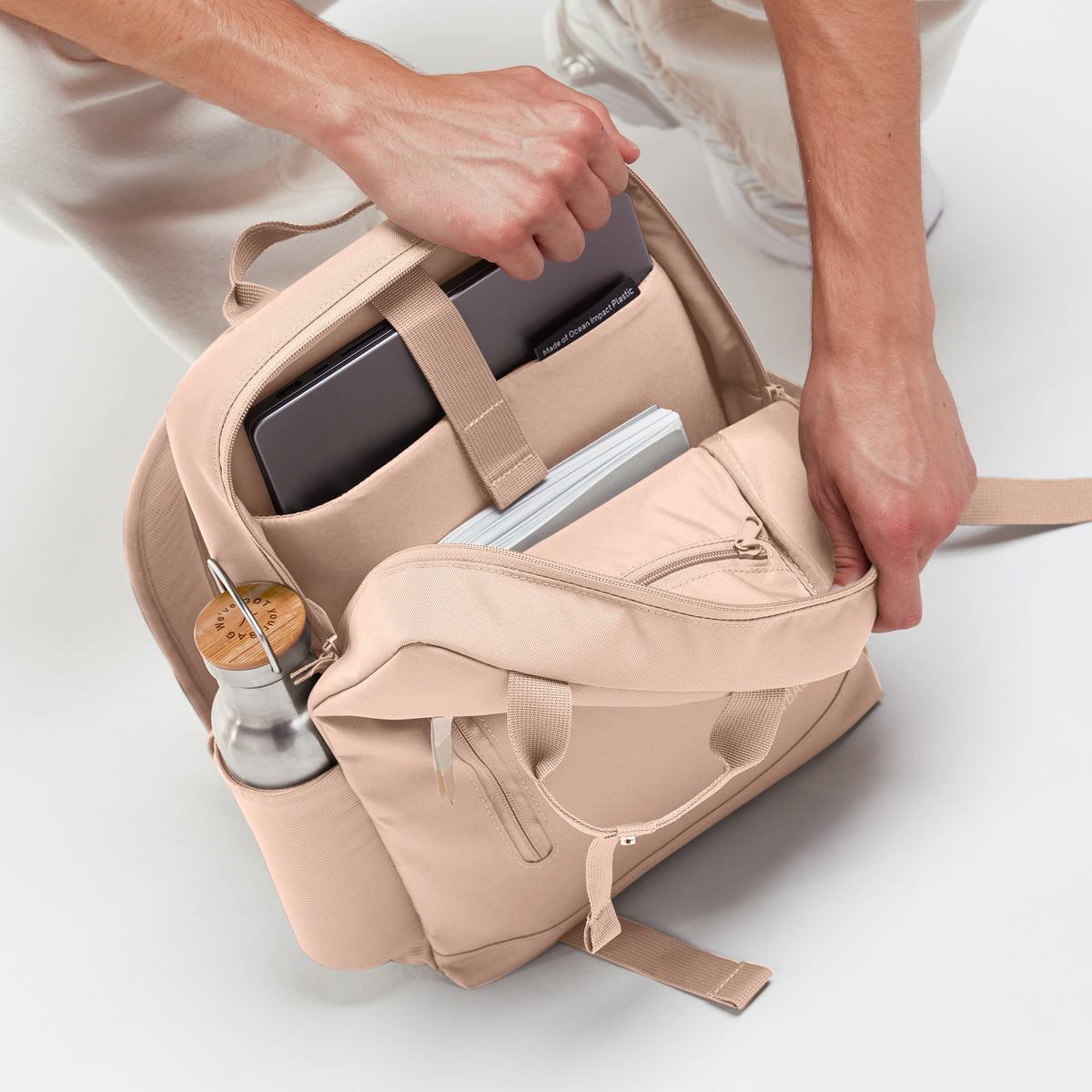 DAYPACK 2.0 MONOCHROME EDITION Rucksack in pearl (helles Puder-Rosa) geöffnet, Person greift hinein.