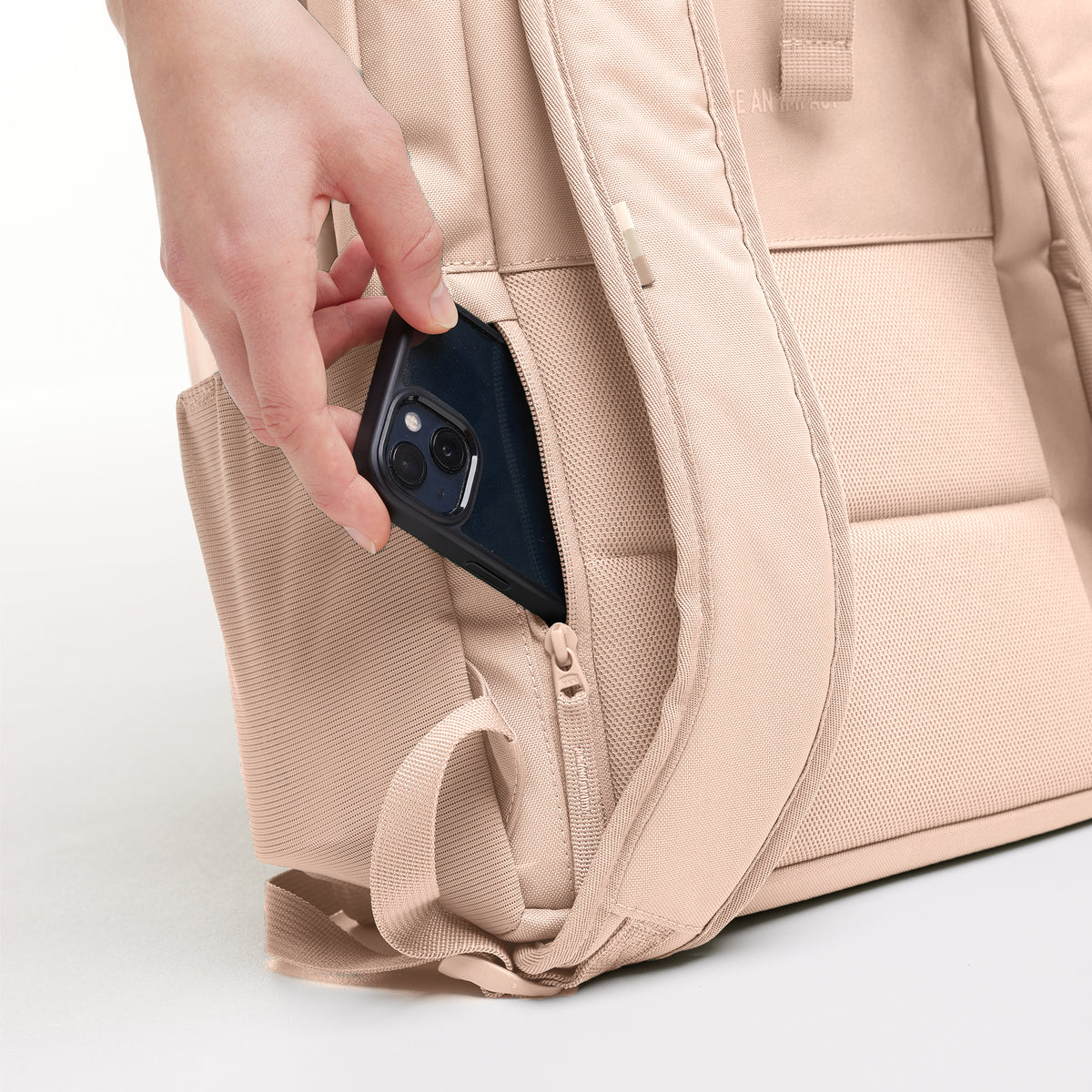 DAYPACK LOOP Rucksack in pearl (helles Puder-Rosa), eine Hand steckt Smartphone in Seitentasche.