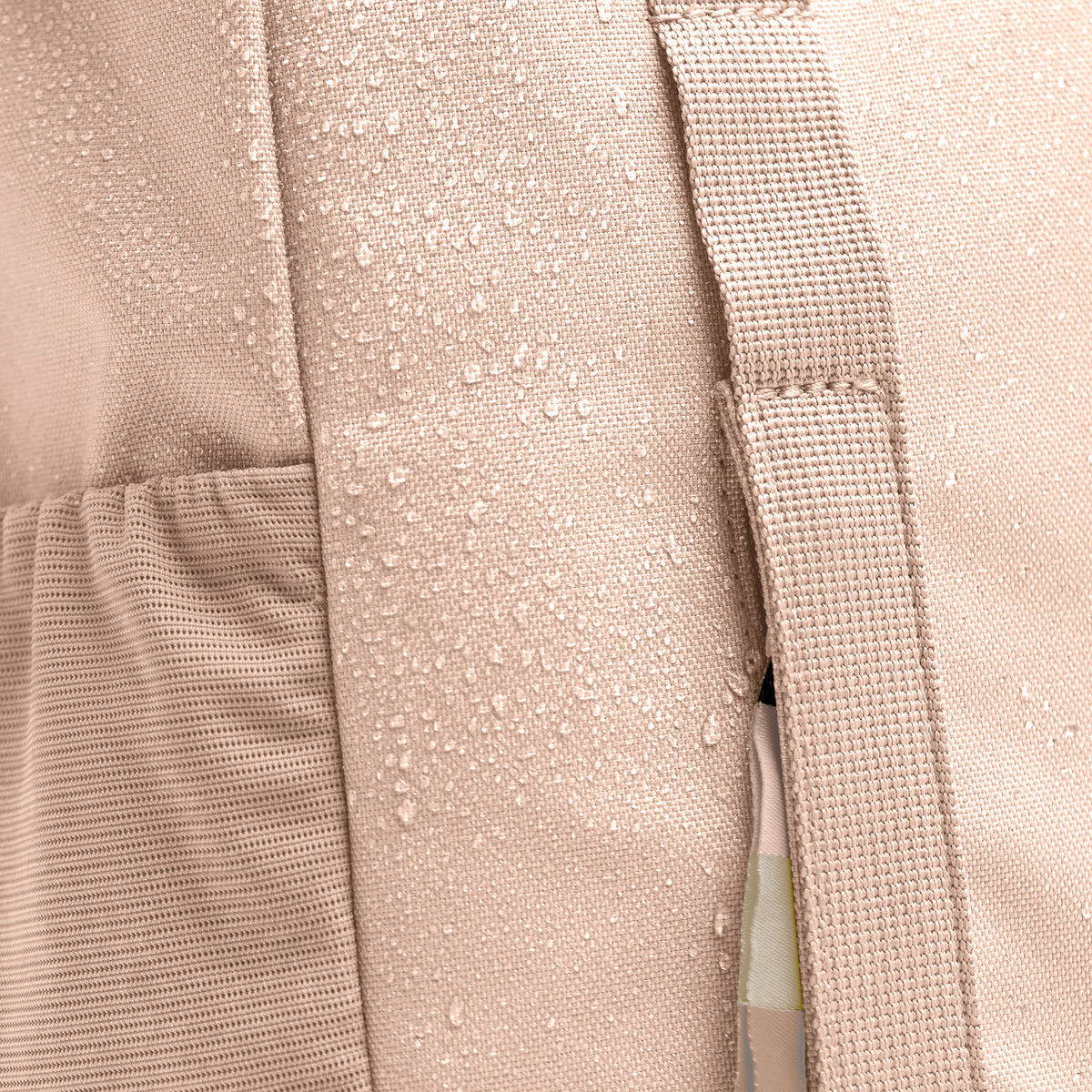DAYPACK LOOP MONOCHROME EDITION Rucksack in pearl (helles Puder-Rosa) Detailaufnahme des Stoffs mit Wassertropfen.