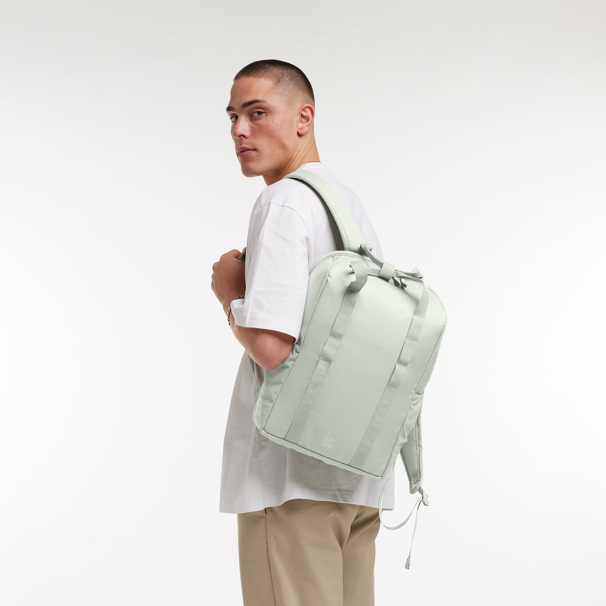 DAYPACK LOOP Rucksack in eel (sehr helles Grün/Mint) von einem Mann auf dem Rücken getragen.