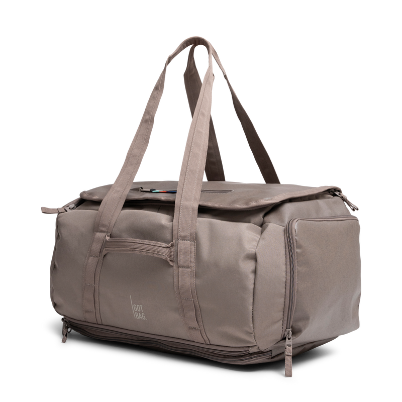 DUFFLE PACK Tasche in oyster (klassisches Taupe-Braun) in diagonaler Ansicht.