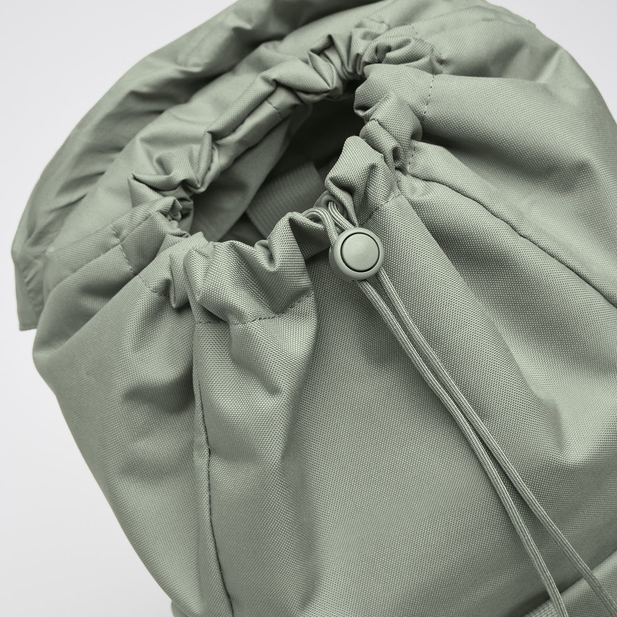 FLAP PACK Rucksack in bass (Salbeigrün) als Detailaufnahme der Zugbandschließung.