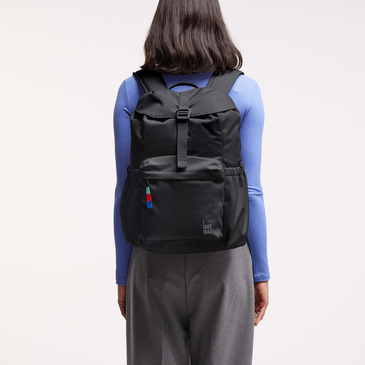 FLAP PACK Rucksack in black (Schwarz) von einer Frau als Rucksack auf dem Rücken getragen.
