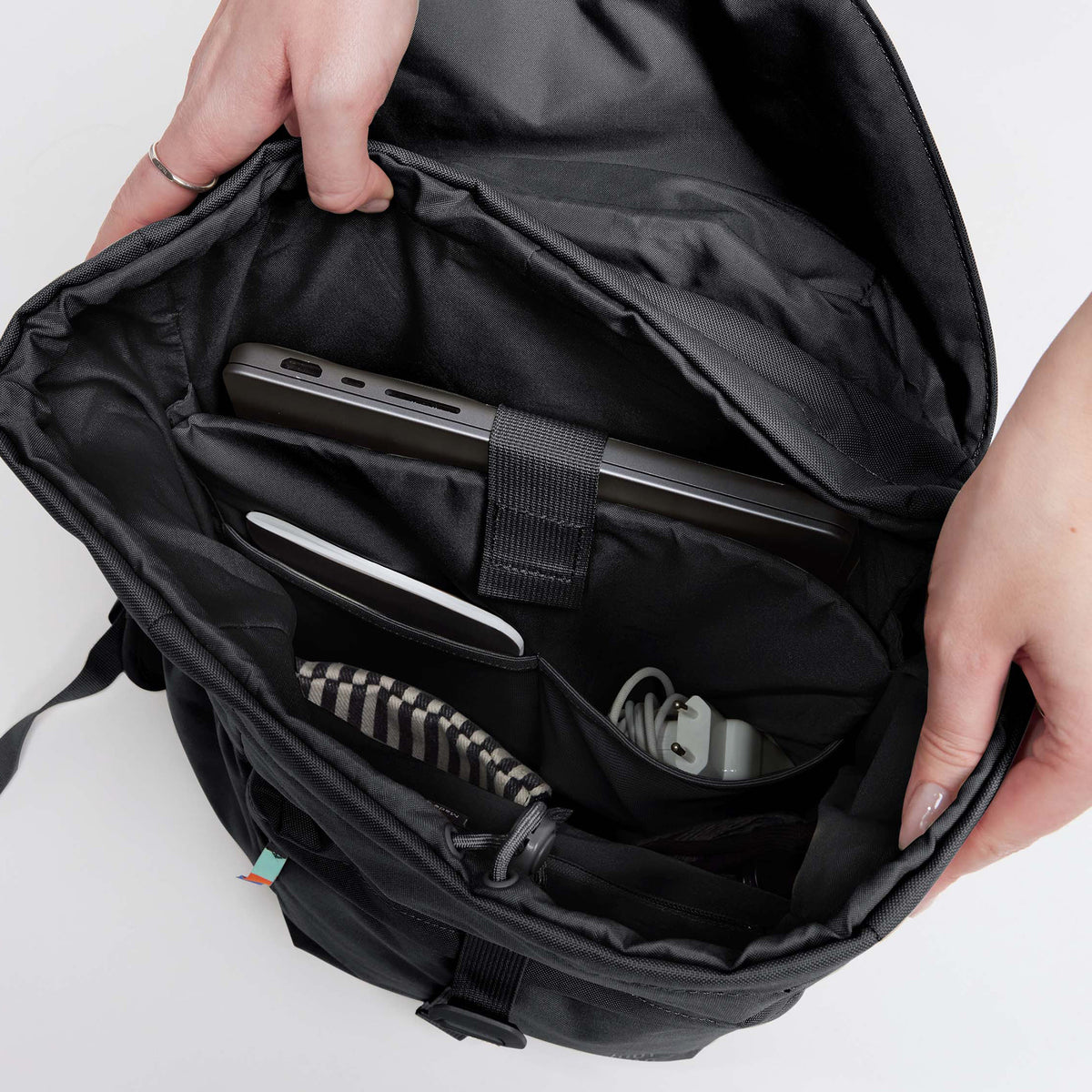 FLAP PACK Rucksack in black (Schwarz), eine Frau hält ihn offen, zeigt das Innenleben mit Laptop und Zubehör.
