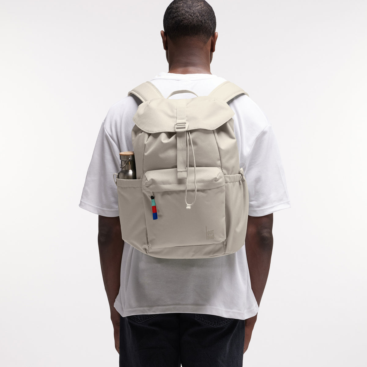 FLAP PACK Rucksack in soft shell (warmes Cremeweiß) von einem Mann als Rucksack auf dem Rücken getragen.